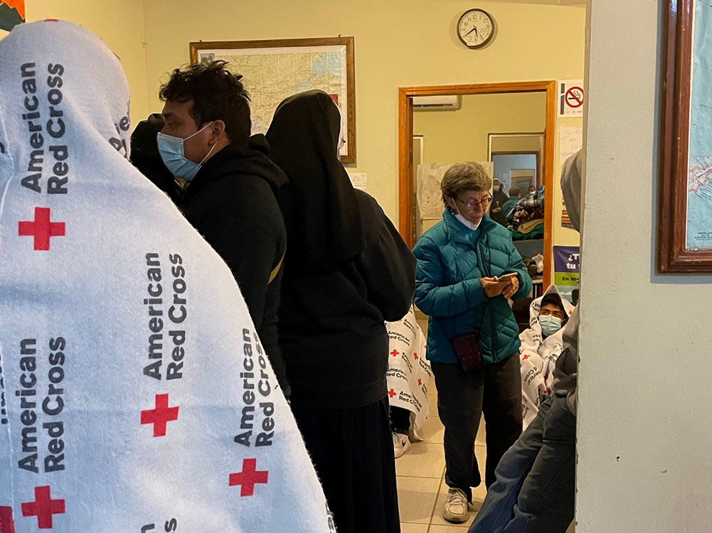 Sr. Judy Bourg (in green coat), a School Sister of Notre Dame, speaks with volunteers and returned migrants on an early morning in October 2021 at the migrant resource center in Agua Prieta, Mexico. (Peter Tran)