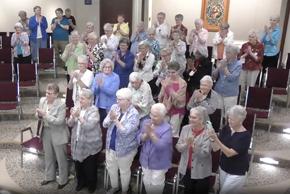 Sisters in the Adrian Dominican auditorium in Adrian, Michigan, give Dominican Sr. Elise García a standing ovation at the conclusion of her Aug. 11 presidential address to the Leadership Conference of Women Religious. (GSR screenshot)