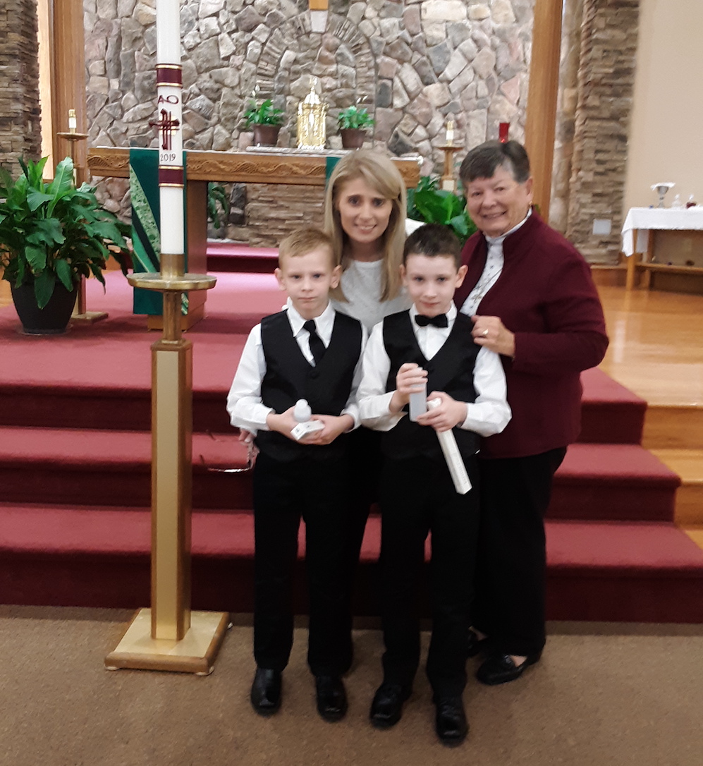 Dominican Sr. Liz Engel, right, with two brothers and their adoptive mother at their first Communion in November 2019. The boys now live in New York after being adopted from Texas. (Courtesy of Liz Engel)