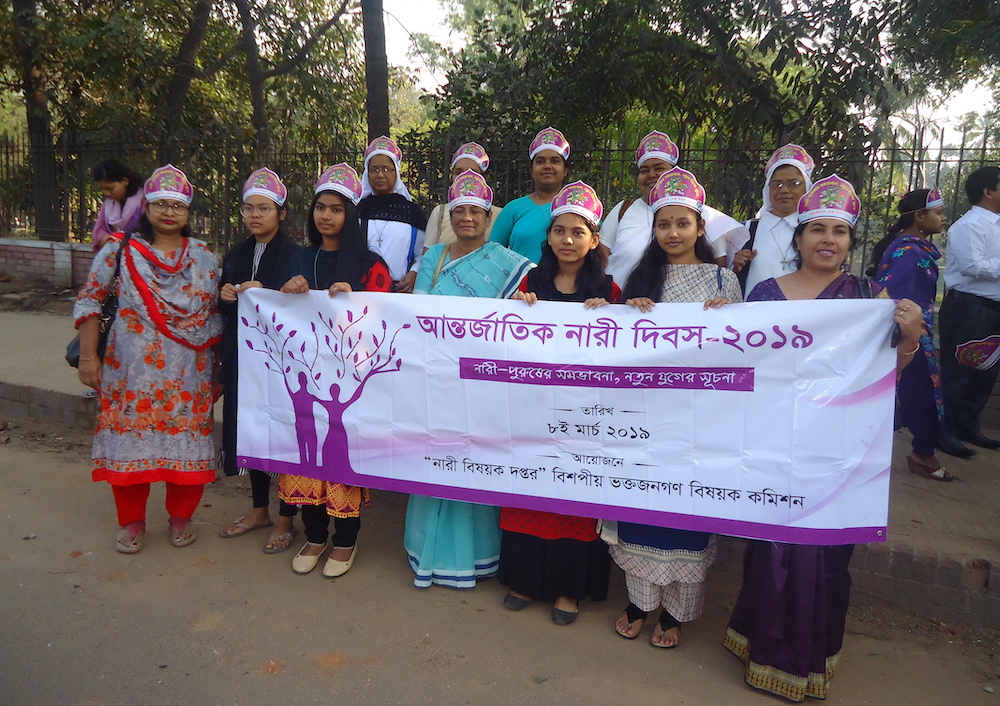 About a dozen women in Bangladesh holding a banner together