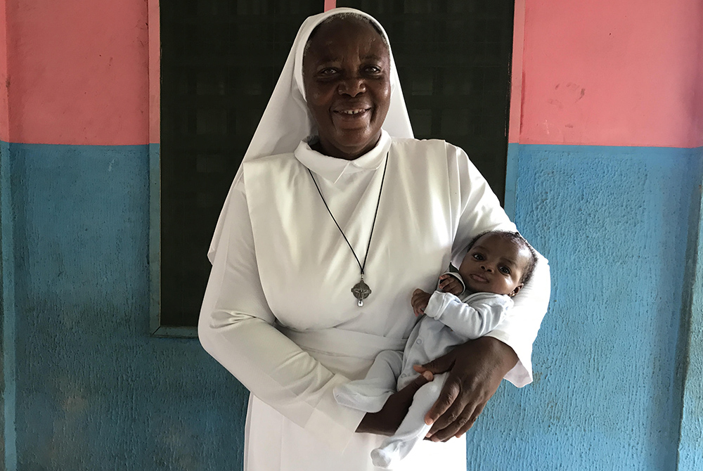 Sr. Matilda Inyang carries a child outside the Mother Charles Walker Children Home May 7 at the Handmaids of the Holy Child Jesus convent in Uyo, Nigeria. Since opening the home in 2007, Inyang has cared for dozens of children. (Valentine Iwenwanne)