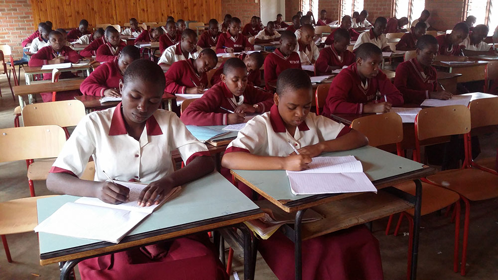 Students seated at desks facing the blackboard in a classroom. 