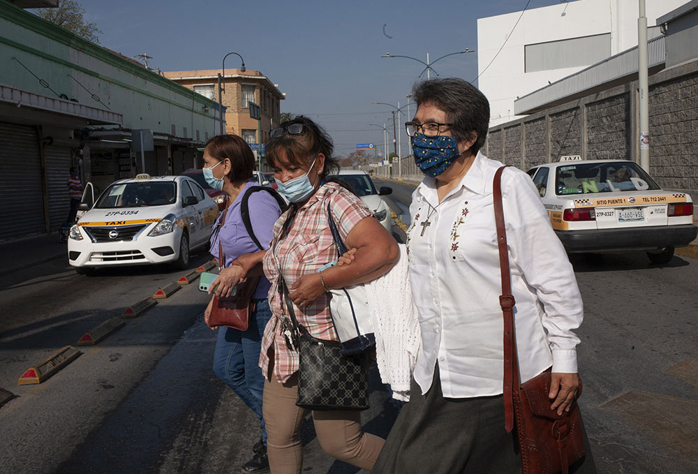 Interfaith Welcome Coalition volunteer Graciela Morgan, from left, El Buen Samaritano shelter coordinator Micaela Ortiz, and Sister Mercedes Castillo make their way through a busy intersection after crossing into Nuevo Laredo, Mexico, on March 27.