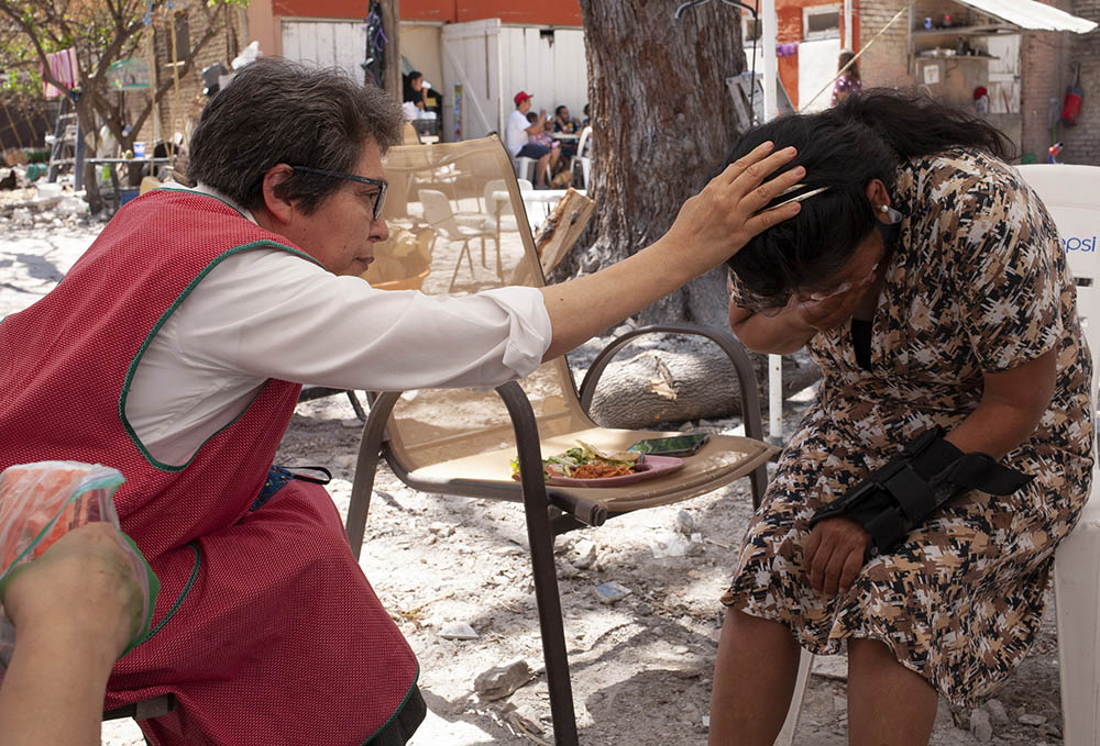 Sr. Mercedes Castillo prays over a Peruvian woman who only wanted to be known by the initials A.N. in the courtyard of the El Buen Samaritano shelter in Nuevo Laredo, Mexico, on March 27. (Nuri Vallbona)