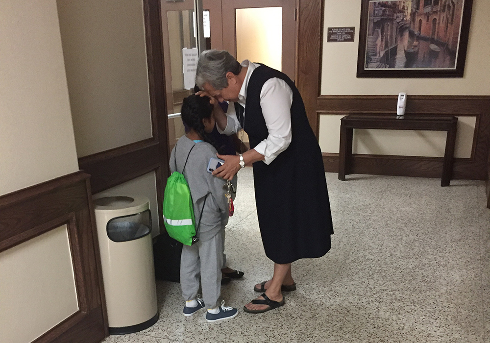 Sr. Norma Pimentel prays with a girl who has been separated from her family in July 2018 at Our Lady of San Juan National Shrine Basilica Hotel.