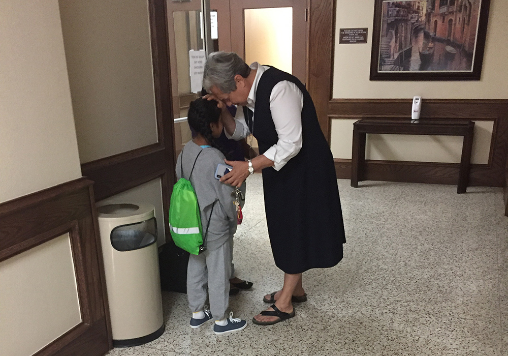 Sr. Norma Pimentel prays with a girl who has been separated from her family in July 2018 at Our Lady of San Juan National Shrine Basilica Hotel. Sr. Norma Pimentel prays with a girl who has been separated from her family in July 2018 at Our Lady of San Juan National Shrine Basilica Hotel.