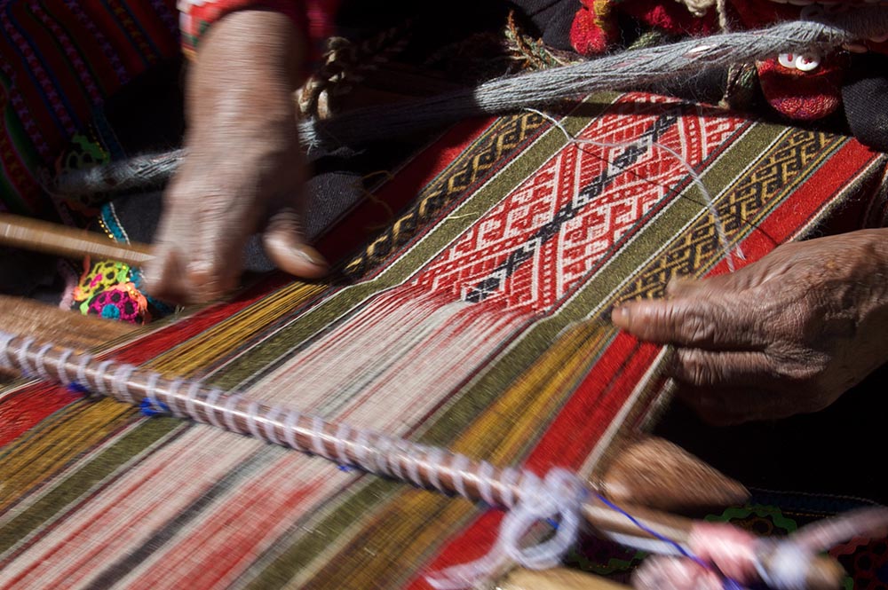 A Quechua woman near Cuzco, Peru, weaves llama yarn. (Flickr/Ken Bosma)