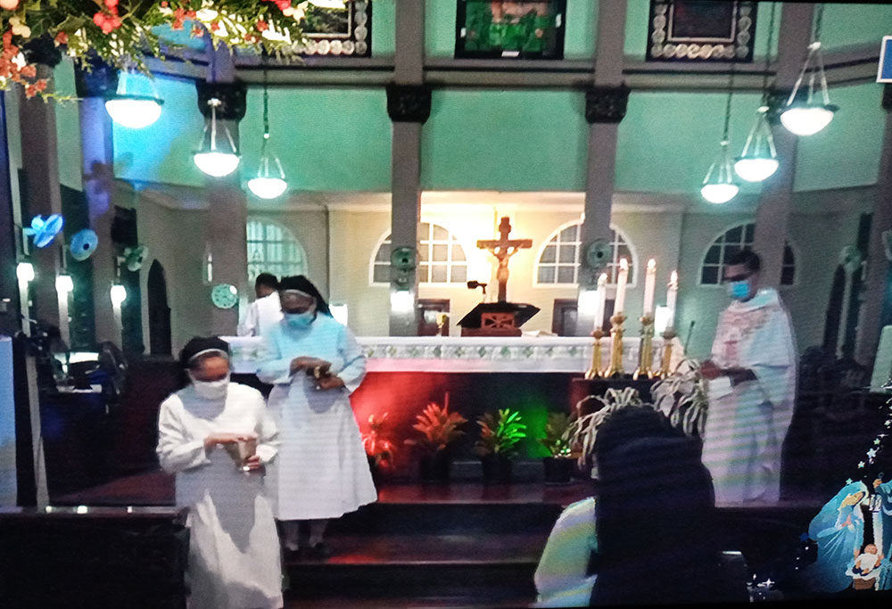 Benedictine sisters with face masks descend from the altar to distribute Communion during a livestreamed Mass. (GSR screenshot/Ma. Ceres P. Doyo)