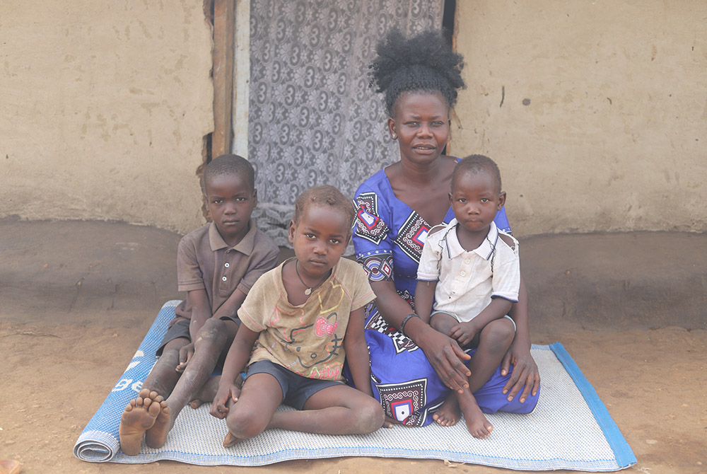 Rose Geno, 30, with her three children sit outside their grass-roofed mud hut at Palabek refugee camp. She is among thousands of refugees who have received seeds and farming support to mitigate food shortage at the camp amid the pandemic. (GSR photo/Doree