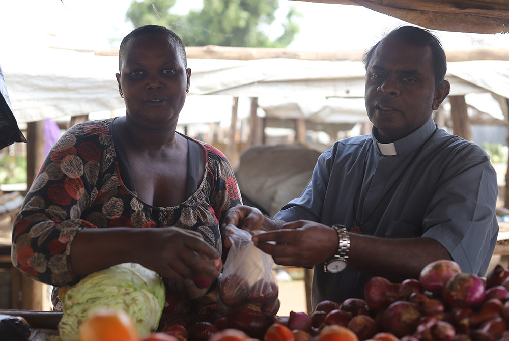 Salesian Fr. Lazar Arasu, director of Don Bosco Palabek, buys tomatoes and onions from south Sudanese refugee at a wholesale vegetable market at Palabek camp Feb. 20 in northern Uganda. (GSR photo/Doreen Ajiambo)