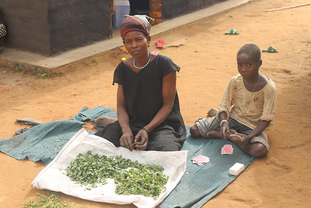 A woman with her child sits on the ground as they prepare vegetables to cook for lunch at Palabek camp Feb. 20 in northern Uganda. (GSR photo/Doreen Ajiambo) 