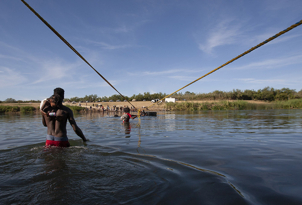 Haitian immigrants make their way along a rope suspended above the Rio Grande on their way to the United States Sept. 22. (Nuri Vallbona)