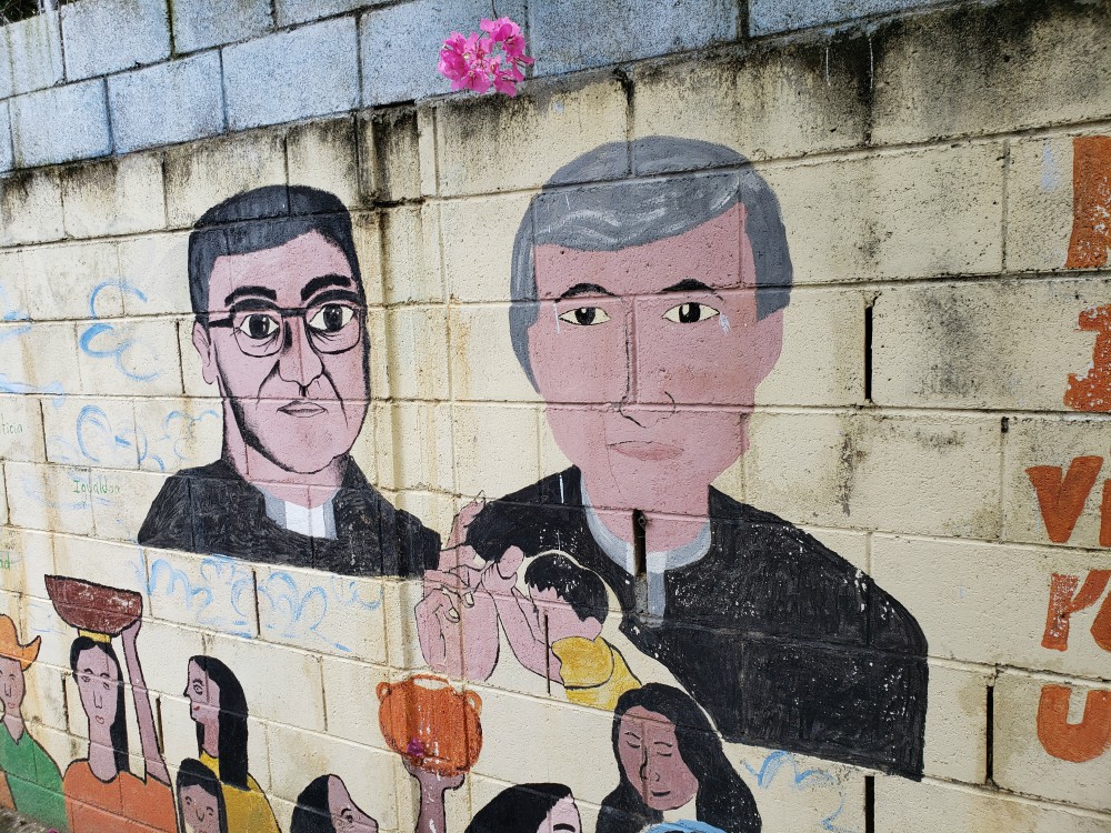 A mural on a wall outside a youth center in Apopa, El Salvador, depicts Archbishop Óscar Romero, left, and Jesuit Fr. Rutilio Grande. The youth center is part of a project of sisters and others called the Color Movement. (GSR / Chris Herlinger) A mural on a wall outside a youth center in Apopa, El Salvador, depicts Archbishop Óscar Romero, left, and Jesuit Fr. Rutilio Grande. The youth center is part of a project of sisters and others called the Color Movement. (GSR / Chris Herlinger)
