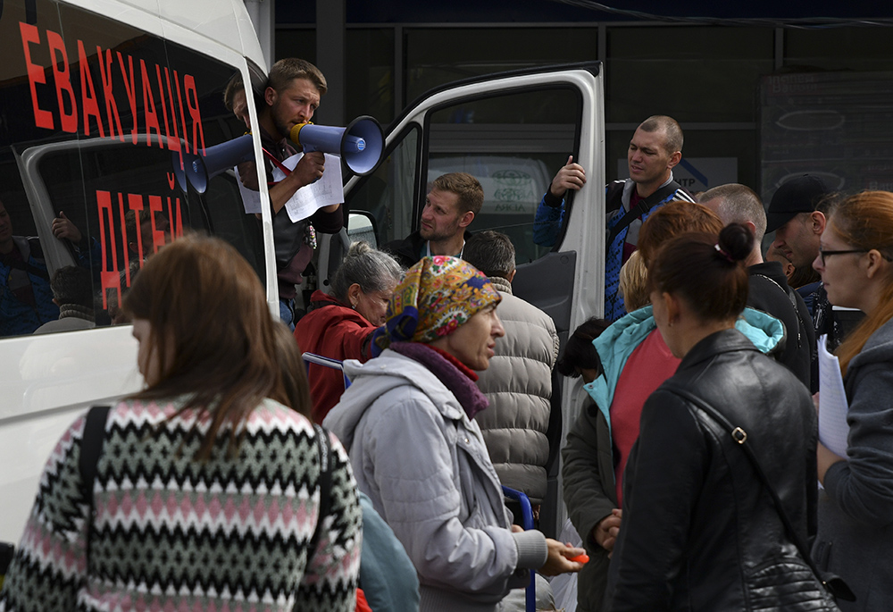 Refugees from war-hit eastern Ukraine stand in line waiting for departure in a refugee center Sept. 15 in Zaporizhzhia, Ukraine. Writing on a bus reads; "Children Evacuation." (AP photo/Andriy Andriyenko) Refugees from war-hit eastern Ukraine stand in line waiting for departure in a refugee center Sept. 15 in Zaporizhzhia, Ukraine. Writing on a bus reads; "Children Evacuation." (AP photo/Andriy Andriyenko)