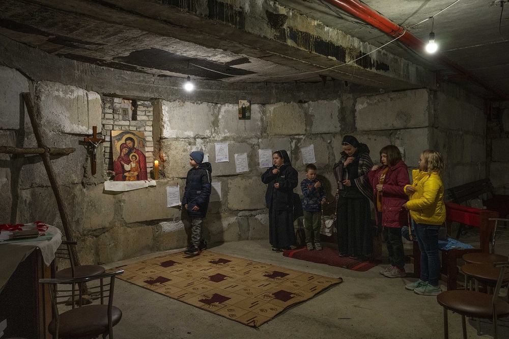 10-year-old Rostyslav Borysenko, who fled besieged Mariupol, left, and displaced children pray with nuns April 6 in a makeshift chapel in a basement the nuns have prepared to take shelter in when air raids go off at the Hoshiv Women Monastery, where nuns