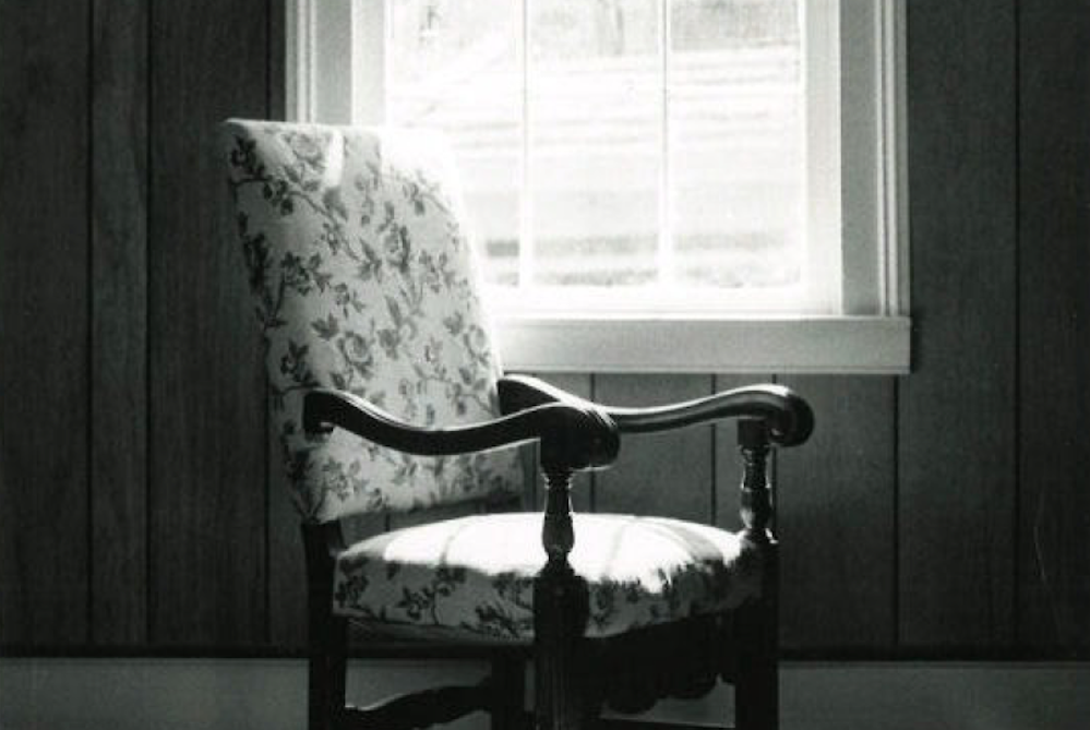 black and white upholstered chair by window with light coming in