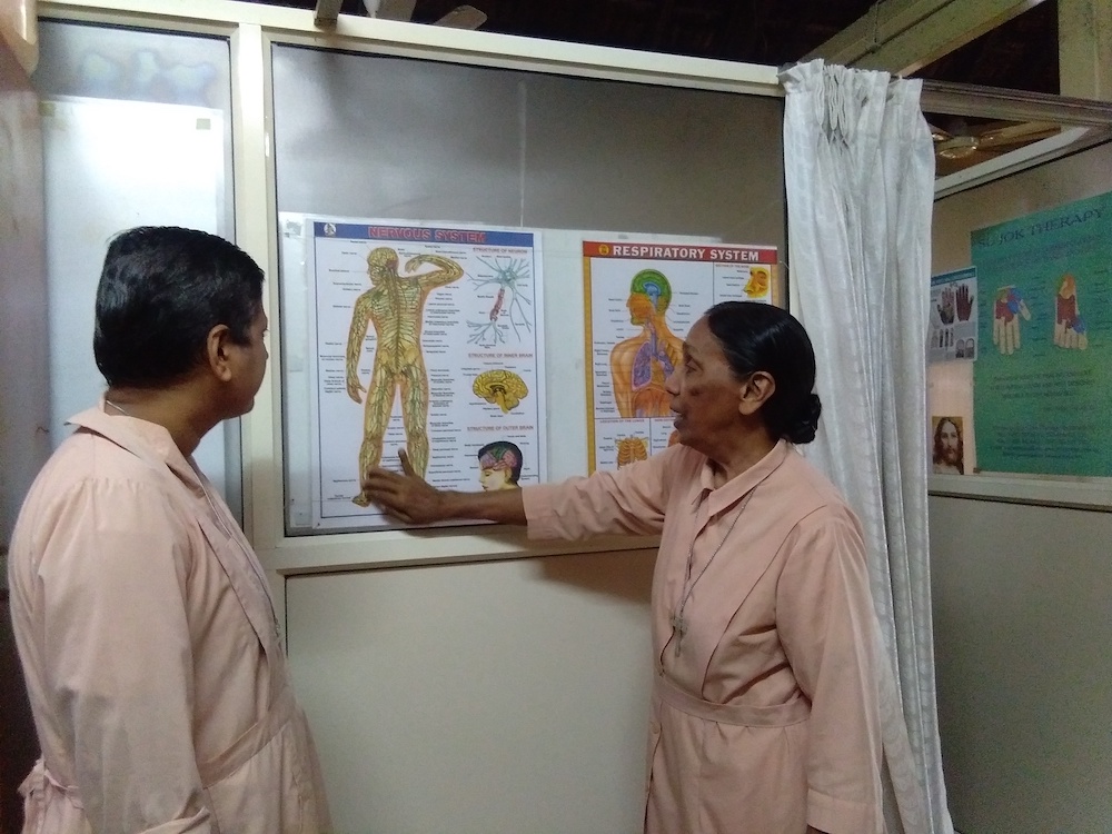 Sr. Scholastica Panthaladikel of the Pious Disciples of the Divine Master, right, discusses acupuncture spots in a human body with Sr. Flavia Aranha in the office of their holistic healing center in Goa, western India. (Lissy Maruthanakuzhy)