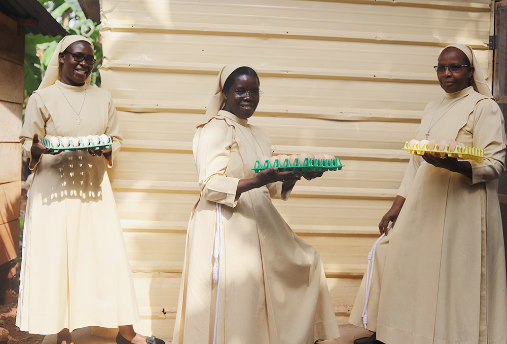 From left, Srs. Florence Anaso, Rose Thumitho and Mary Atema of the Little Sisters of St. Francis of Assisi hold crates of eggs after harvesting them on Feb. 23 in Jinja, Uganda. (Doreen Ajiambo)