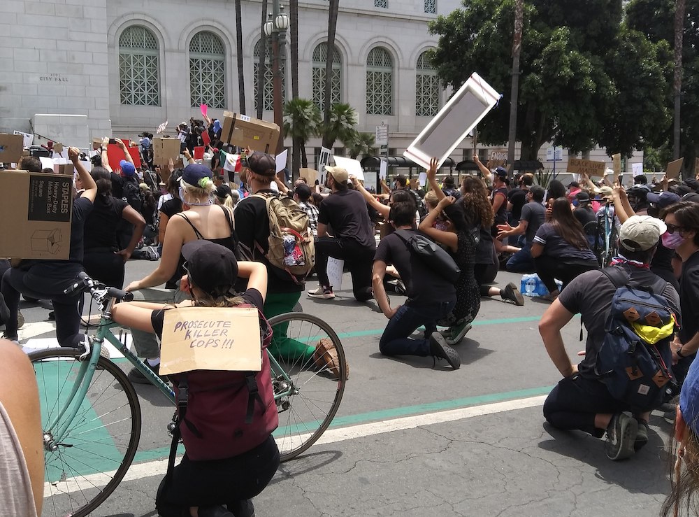 Demonstrators supporting George Floyd and protesting police brutality and killings, especially against Black people, take a knee at City Hall in Los Angeles, for "Blackout Tuesday," June 2 (Wikimedia Commons/Kriddl) Demonstrators supporting George Floyd and protesting police brutality and killings, especially against Black people, take a knee at City Hall in Los Angeles, for "Blackout Tuesday," June 2 (Wikimedia Commons/Kriddl)