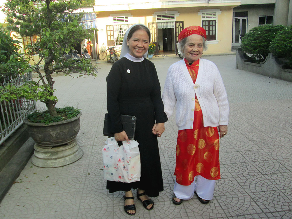 Sr. Maria Bach Thi Tuyen of the Daughters of Our Lady of the Visitation, left, and her mother pay visits to their relatives and neighbors in Phu Cat commune in Hue, Vietnam, during this year's Tet or Lunar New Year festival. (Joachim Pham)