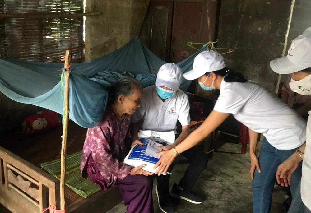 Members of Thap Sang Hy Vong offer Tet gifts of money and rice to an elderly woman Jan. 18 in Huong Tra district in Thua Thien Hue province, Vietnam. (Joachim Pham)