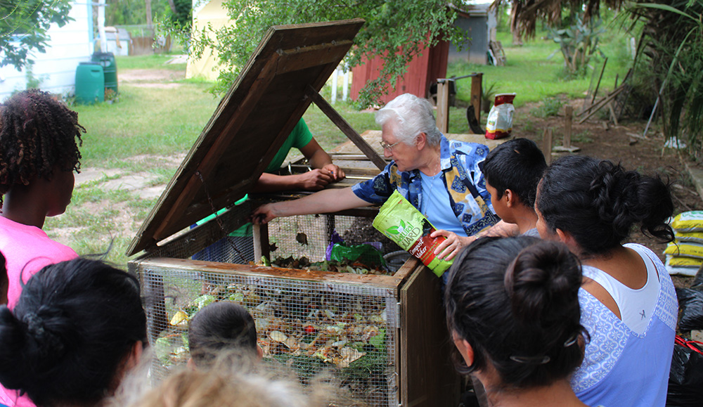 Sr. Thérèse Cunningham of the Sisters of the Holy Spirit and Mary Immaculate, center, teaches guests at La Posada Providencia in San Benito, Texas, how to compost using a bin of fruit peels before the pandemic.