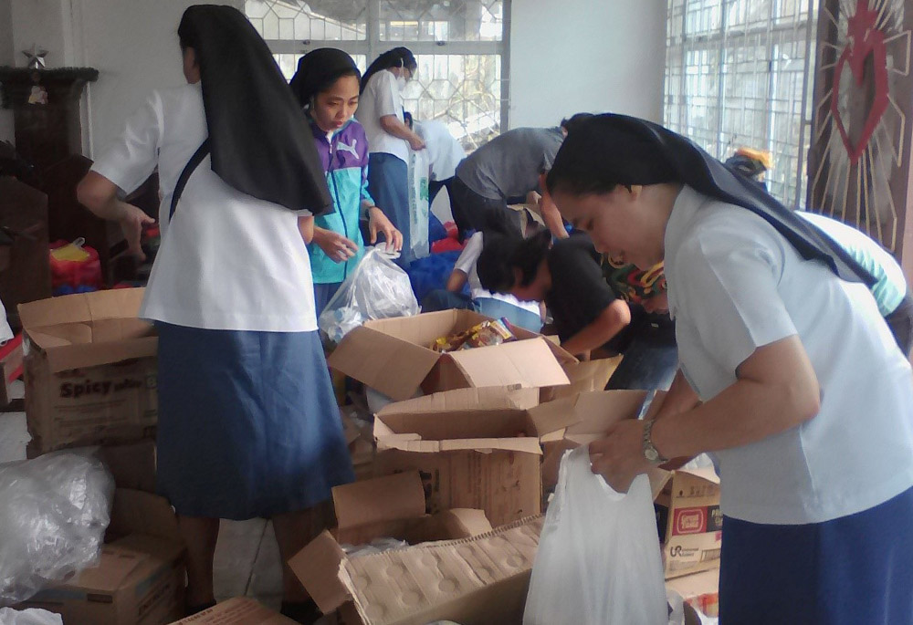 Within days after the typhoon hit, Missionary Sisters of Mary sisters sort through donated goods to repack and send to various communities in need, in Lapu-Lapu City, Cebu province, in the Philippines. (Courtesy of Missionary Sisters of Mary)