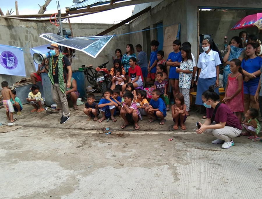 Children and a few adults wait for their parents and relatives who are in line to receive relief goods in one of the distribution areas along a coastal community in Surigao City. (Courtesy of Missionary Sisters of Mary) 