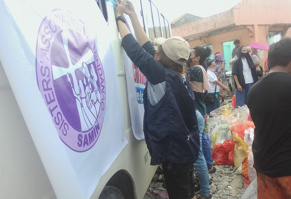 Members of the relief team tie banners displaying Sisters Association of Mindanao and Balsa Mindanao onto their vehicles so the people can identify them. (Courtesy of Missionary Sisters of Mary) 