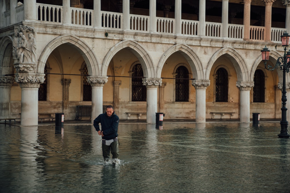 A man wades through knee-high flood waters in St. Mark's Square, Venice, Italy. (Unsplash/Egor Gordeev)