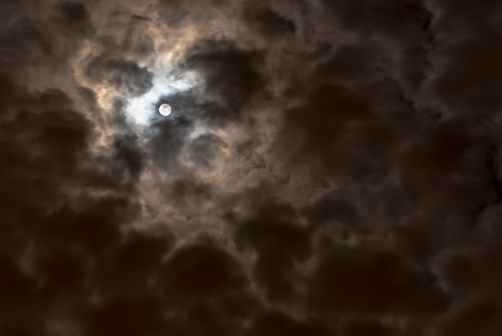 Moon obscured by clouds at night  (Unsplash/Jason Blackeye)