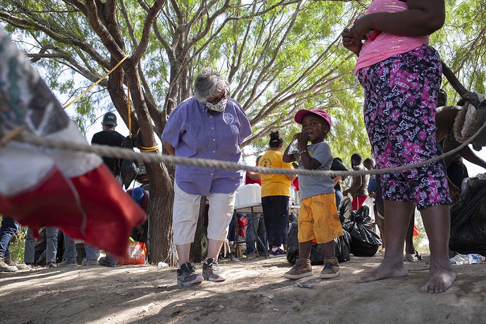 Sr. Ursula Herrera banters with a 2-year-old Haitian boy who is watching his father wade through the Rio Grande toward an immigration camp in Ciudad Acuña, Mexico, Sept. 22.