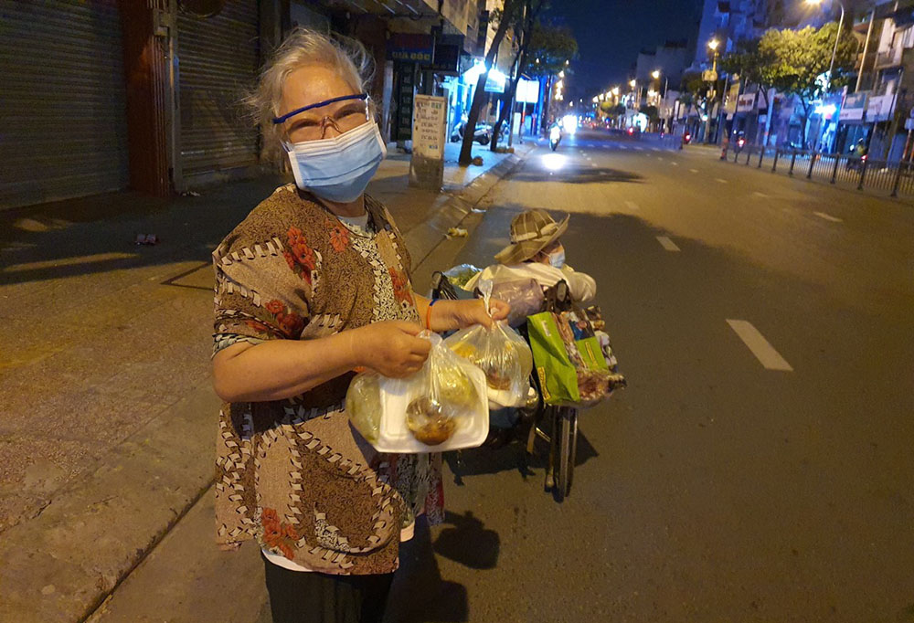 A woman who collects used items on the street at night receives food from volunteers in Ho Chi Minh City, Vietnam. (Courtesy of Mary Pham Thi Huong Huong)