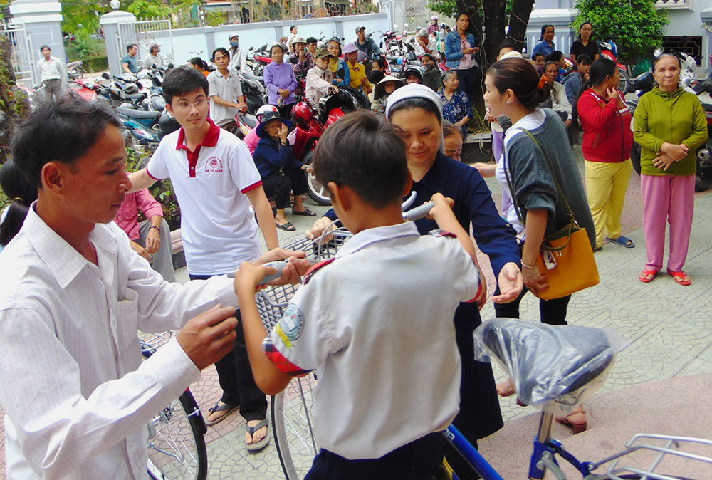 Sr. Maria Nguyen Thi Hong of the Daughters of Our Lady of the Visitation offers a bike to a student in Hue, Vietnam. (Joachim Pham)