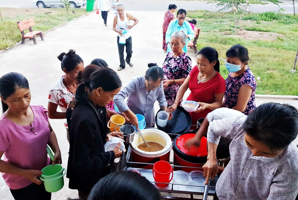 Lovers of the Holy Cross of Hue Sr. Anna Nguyen Thi Hien, center, serves chao to patients' relatives in the hospital yard of Quang Tri General Hospital. (Joachim Pham)