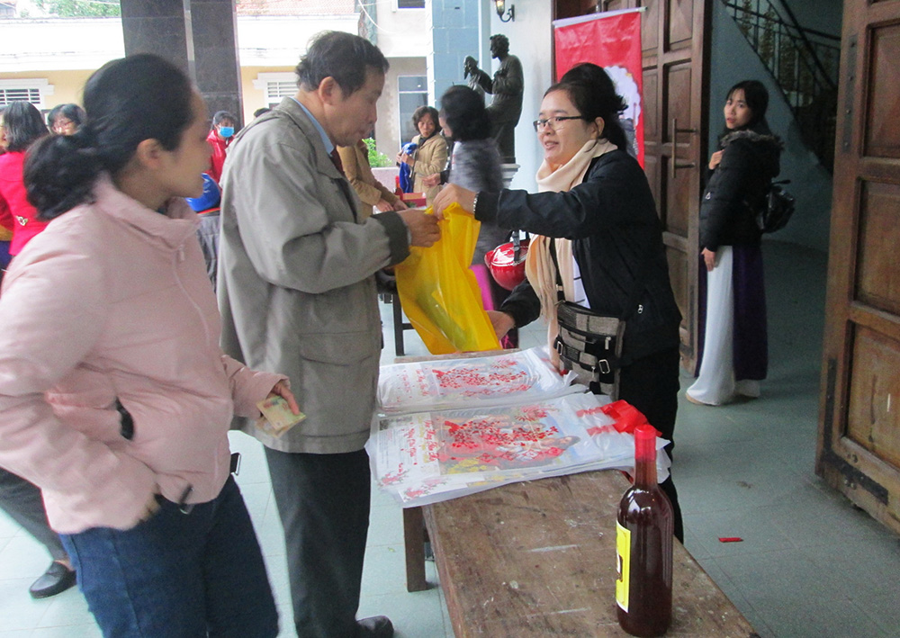 St. Paul de Chartres Sr. Nguyen Thi Huong sells 2021 calendars and wine at Gia Hoi Church on Dec. 6. (Joachim Pham)