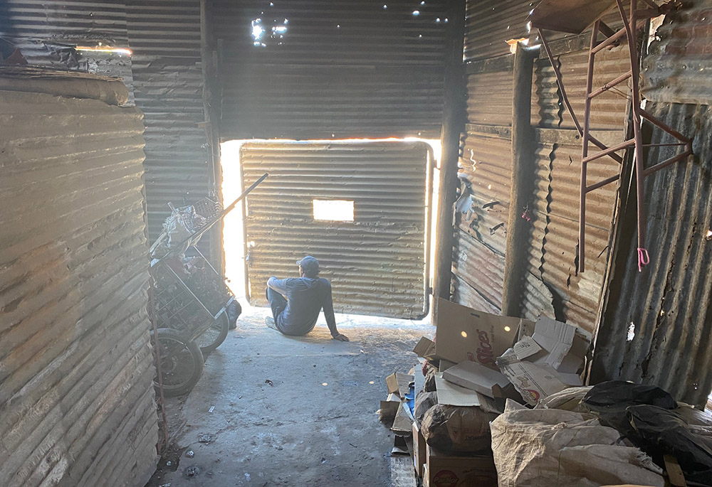 Un hombre se asoma a la puerta de su vivienda. A su lado hay un carro que los cartoneros utilizan para recoger cartón y otros materiales para cambiarlos por pequeñas cantidades de dinero. (Fotografía de GSR/Soli Salgado)