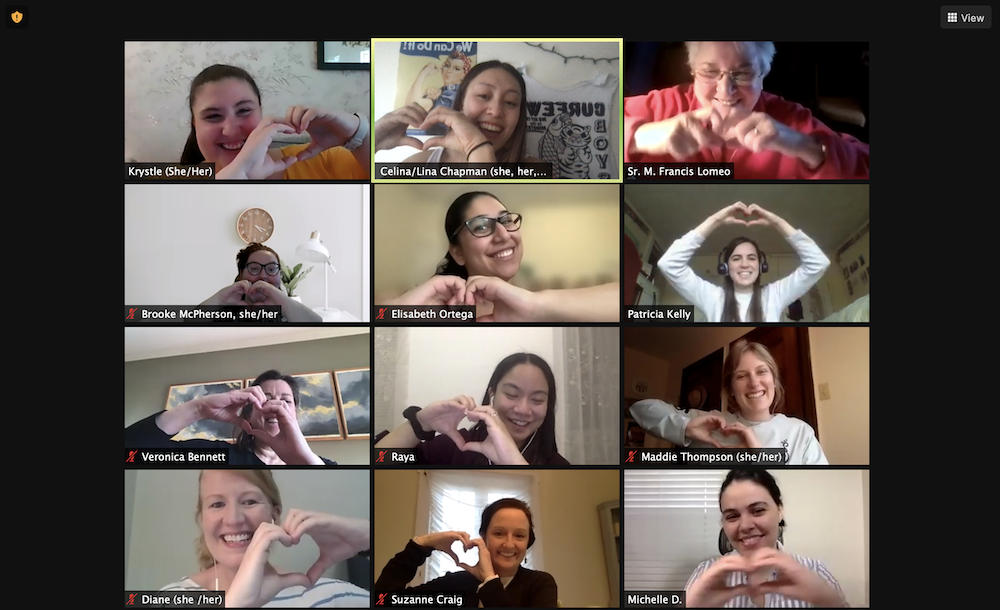 Nine women making heart symbol with their hands while tiled on a Zoom call