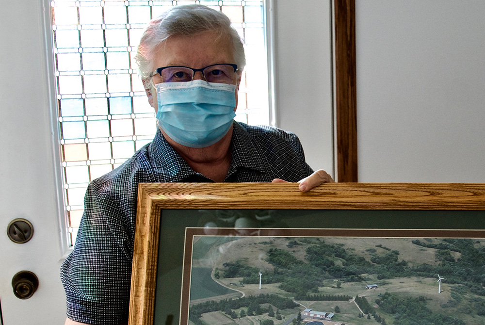 Benedictine Sr. Paula Larson holds a photo of the community's former convent, which had two wind turbines, the first commercial wind turbines in North Dakota. (GSR photo/Dan Stockman)