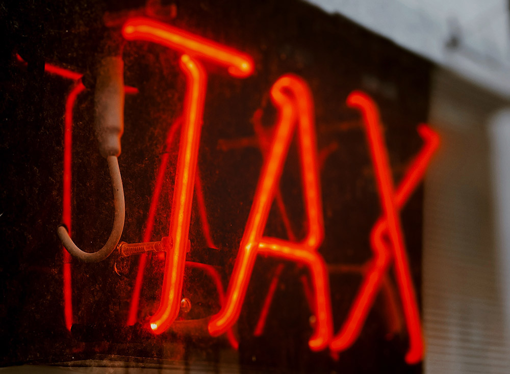 Neon tax sign (Unsplash/Jon Tyson)