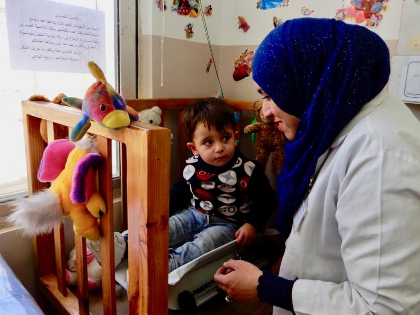 A nurse at the Pontifical Mission Mother of Mercy Clinic in Zarqa weighs a young Syrian refugee ahead of his vaccinations.