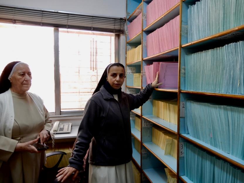 Dominican Sr. Habiba Toma Binham, left, and Sr. Maryan Nahla Kame in the records room of the Pontifical Mission clinic in Zarqa, are refugees themselves, having fled Iraq in 2014.