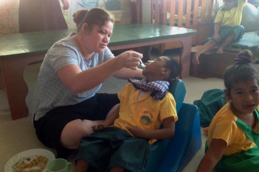Sr. Kawi Arebonto feeds a child who lives with disabilities.