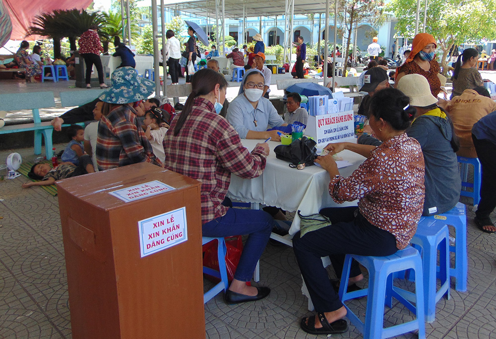 Pilgrims make donations and give their intentions of prayers to a nun. (Joachim Pham)