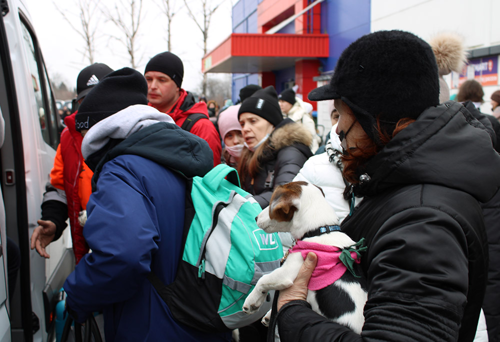 New refugees, some holding pets, arriving from Ukraine board vans at a reception center at Przemyśl, in southeastern Poland, destined for other cities in Poland or elsewhere in Europe. (GSR photo/Chris Herlinger)