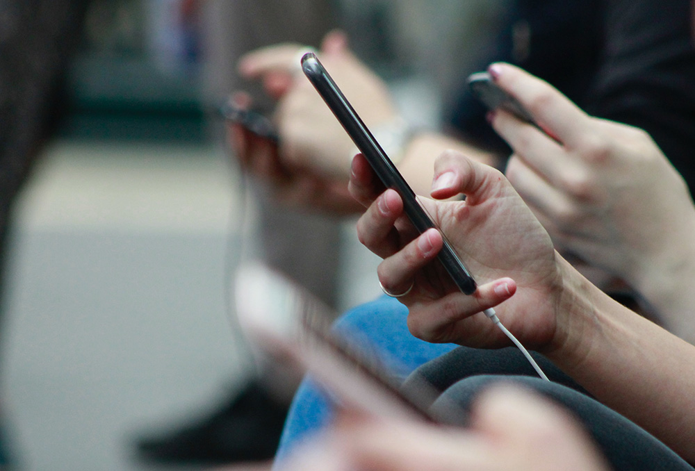 Scrolling through phones (Unsplash/Robin Worrall)