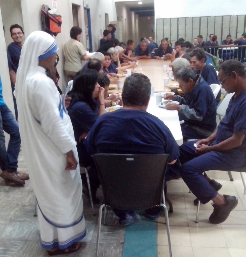 Following the humanitarian activity at La Merced, dinners are handed out at the nearby dormitory. Sister Marinus, left, stands next to a group at one of the three long tables. (GSR photo / George Rodriguez)