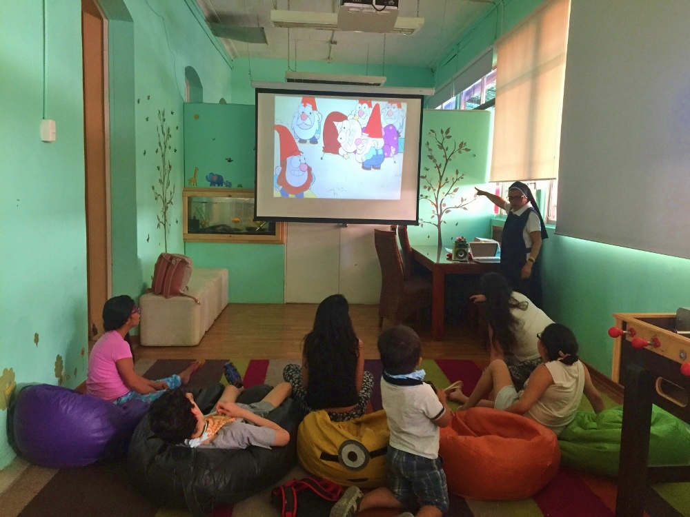 Sr. Nora Valencia and children who live in Santa Clara Home watch television at the orphanage in Santiago, Chile. (GSR photo / Soli Salgado)