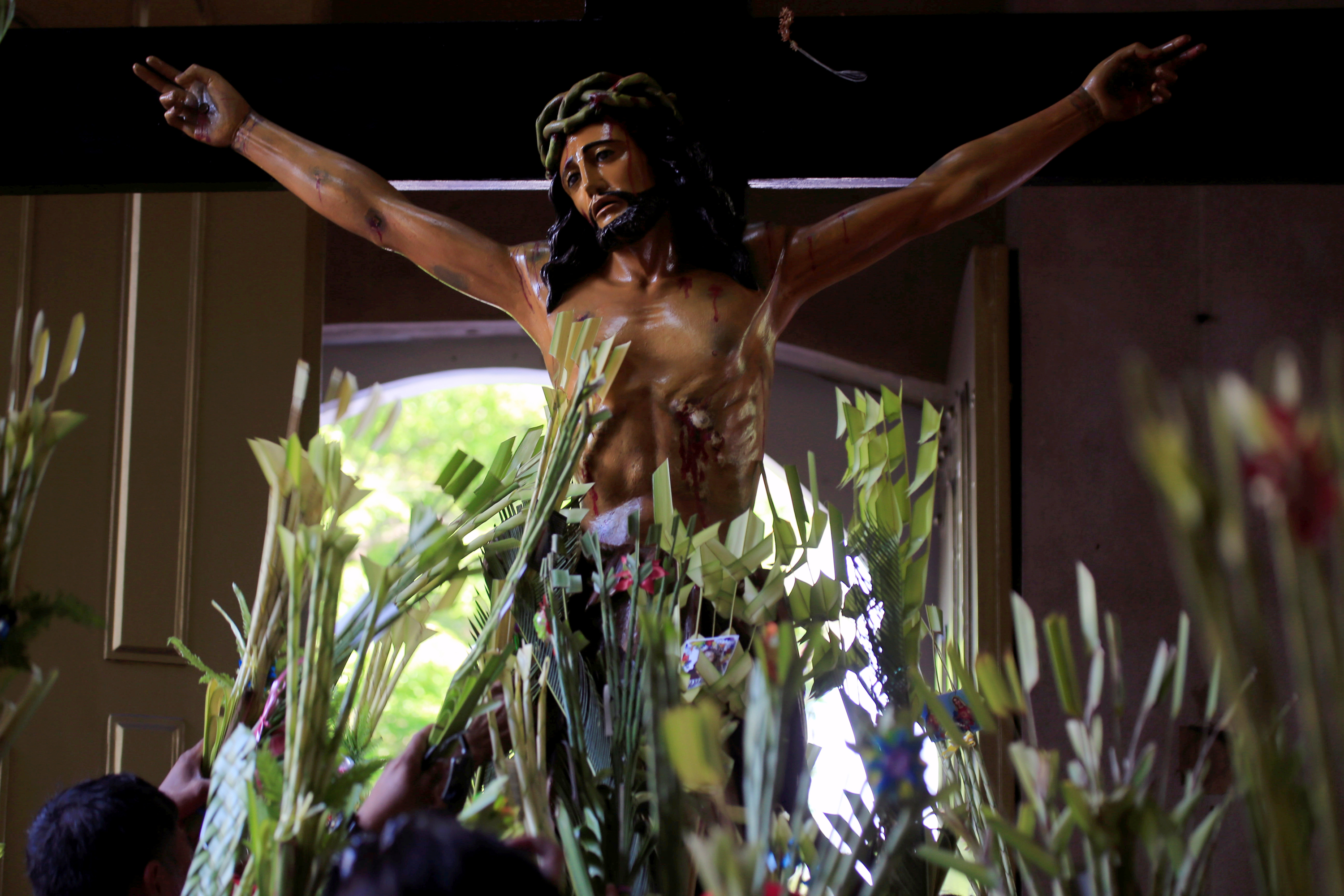 Worshippers wave palm fronds in front of a crucifix during Palm Sunday Mass on March 25 in Manila, the Philippines. (CNS / Reuters / Romeo Ranoco)