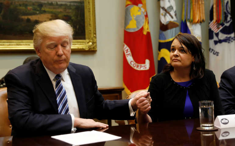 U.S. President Donald Trump clasps hands with Carrie Couey of Colorado during a meeting about healthcare at the White House March 13, 2017. (Reuters/Kevin Lamarque)
